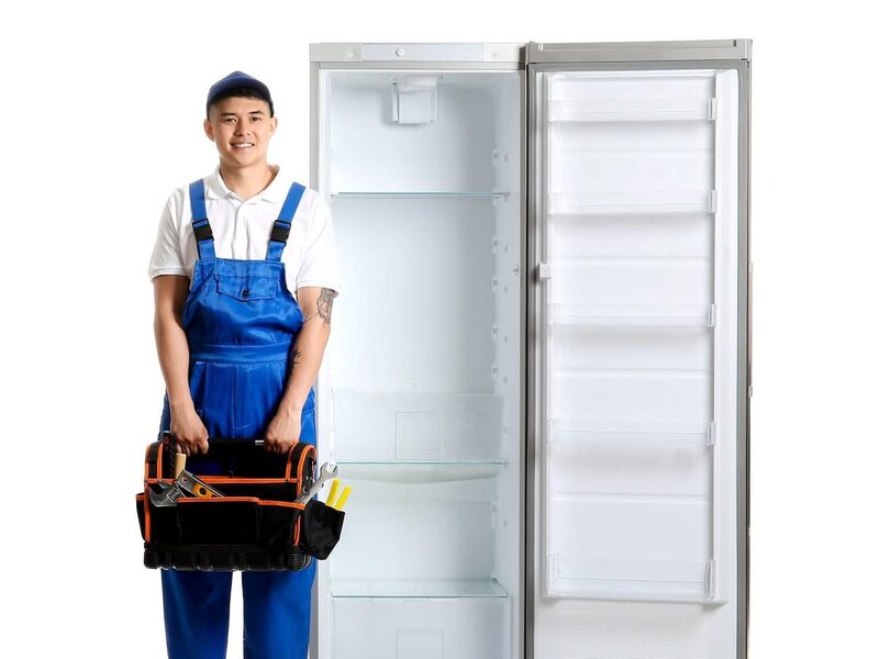 Technician with a toolbox beside an open upright freezer